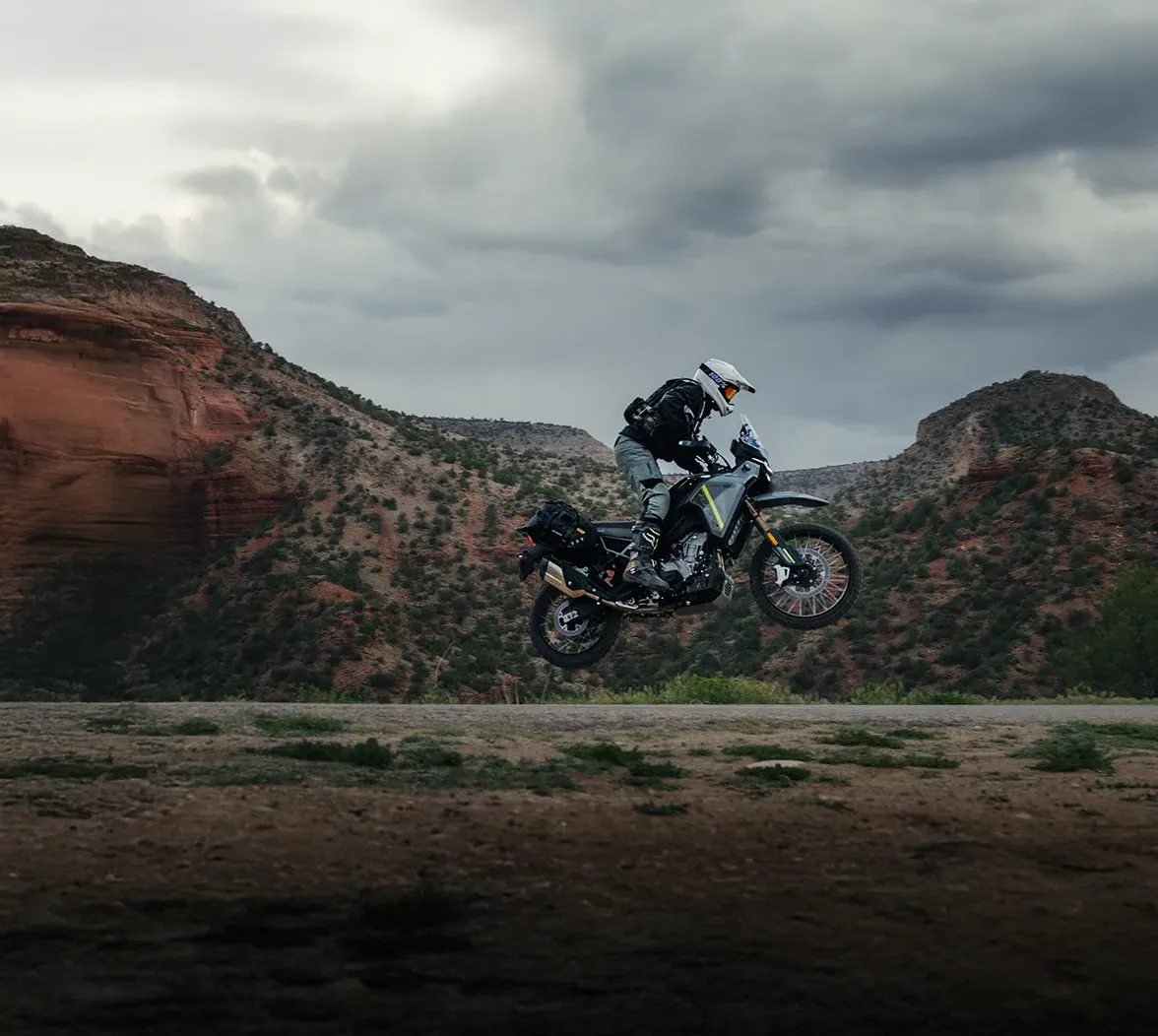 Piloto saltando com a moto de aventura CFMOTO sobre um cânion no deserto